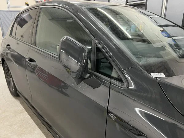 VW Golf Mk8 with an exterior mirror folded towards the car