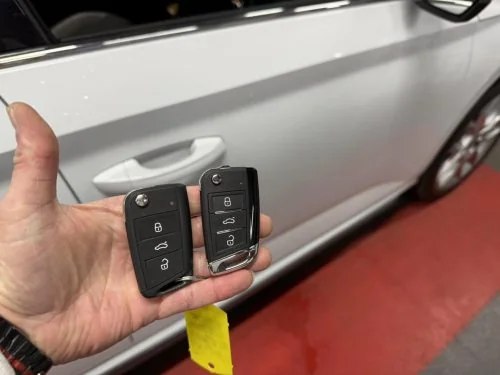 Two Škoda remote keys held beside a white Kamiq