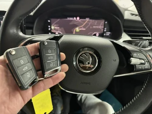 Two Škoda remote keys held in front of the steering wheel
