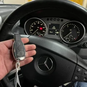Mercedes-Benz remote key held in front of the steering wheel and instrument cluster