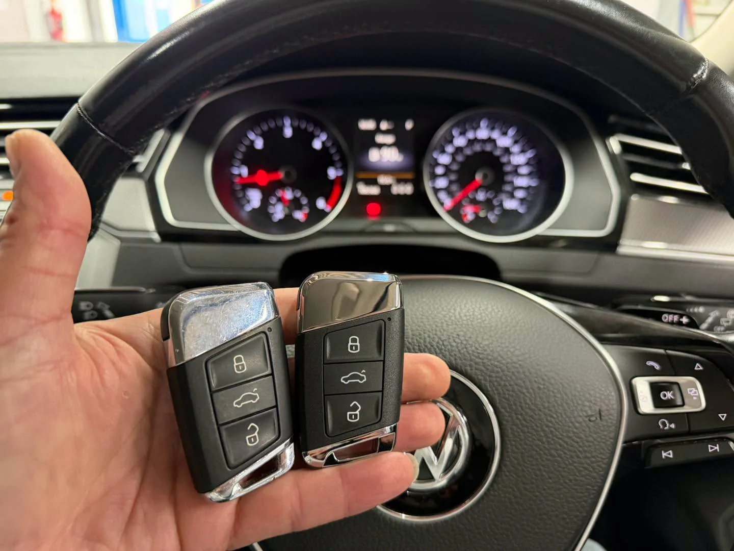 Two Passat B8 remote keys in front of the instrument cluster